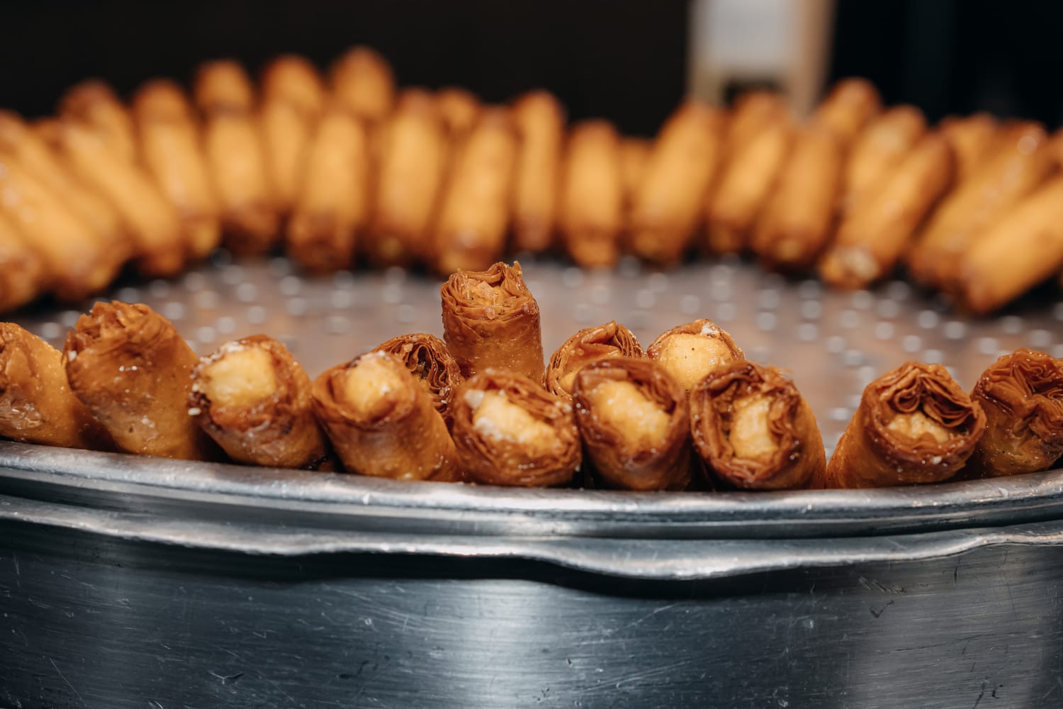 A tray of znood el sit with the open ends facing out, showing the thick ashta cream inside the fried filo.